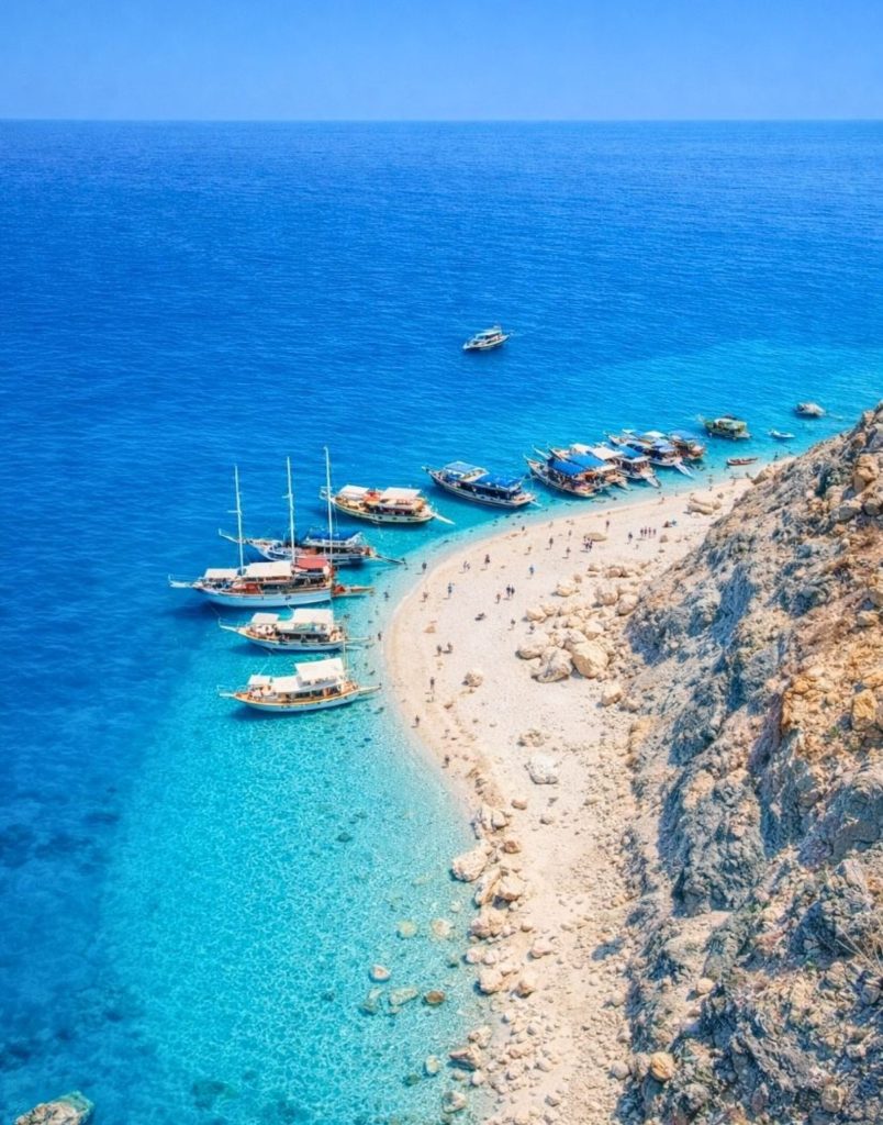 Aerial view of Suluada Island beach with tour boats and deep blue Mediterranean water