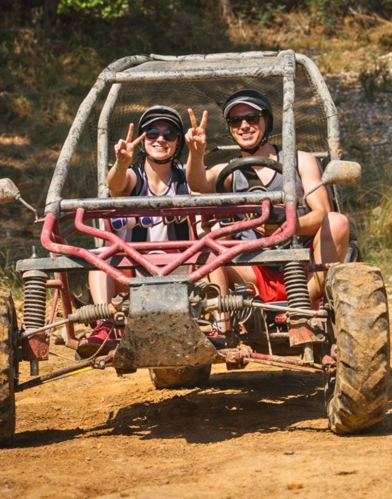 Happy couple showing peace signs in muddy buggy on Alanya buggy safari