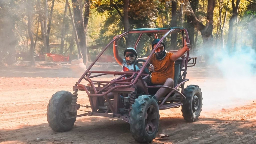 Two visitors driving buggy on dusty red dirt trail in forest on Alanya buggy safari