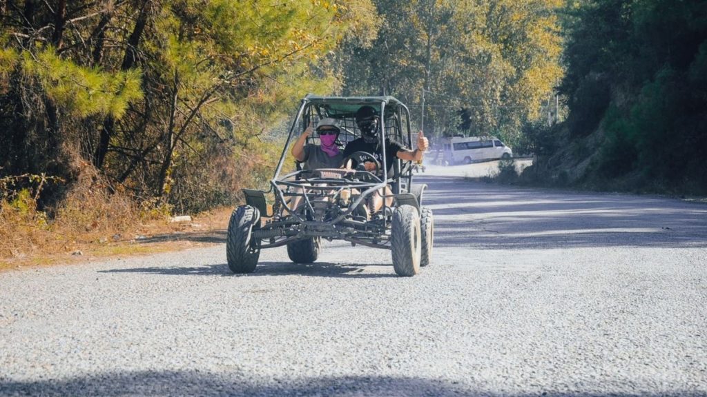Two happy visitors giving thumbs up in buggy on forest road in Alanya