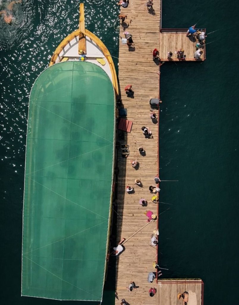 Aerial view of Green Canyon tour boat at wooden pier with visitors at swim break