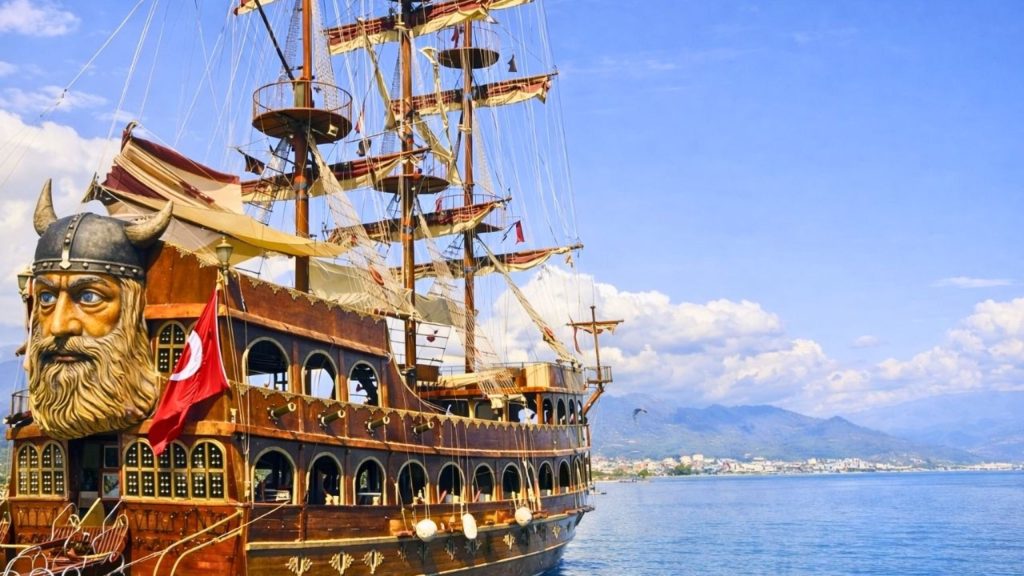 Viking themed pirate boat with Turkish flag at Alanya harbour with mountains in background