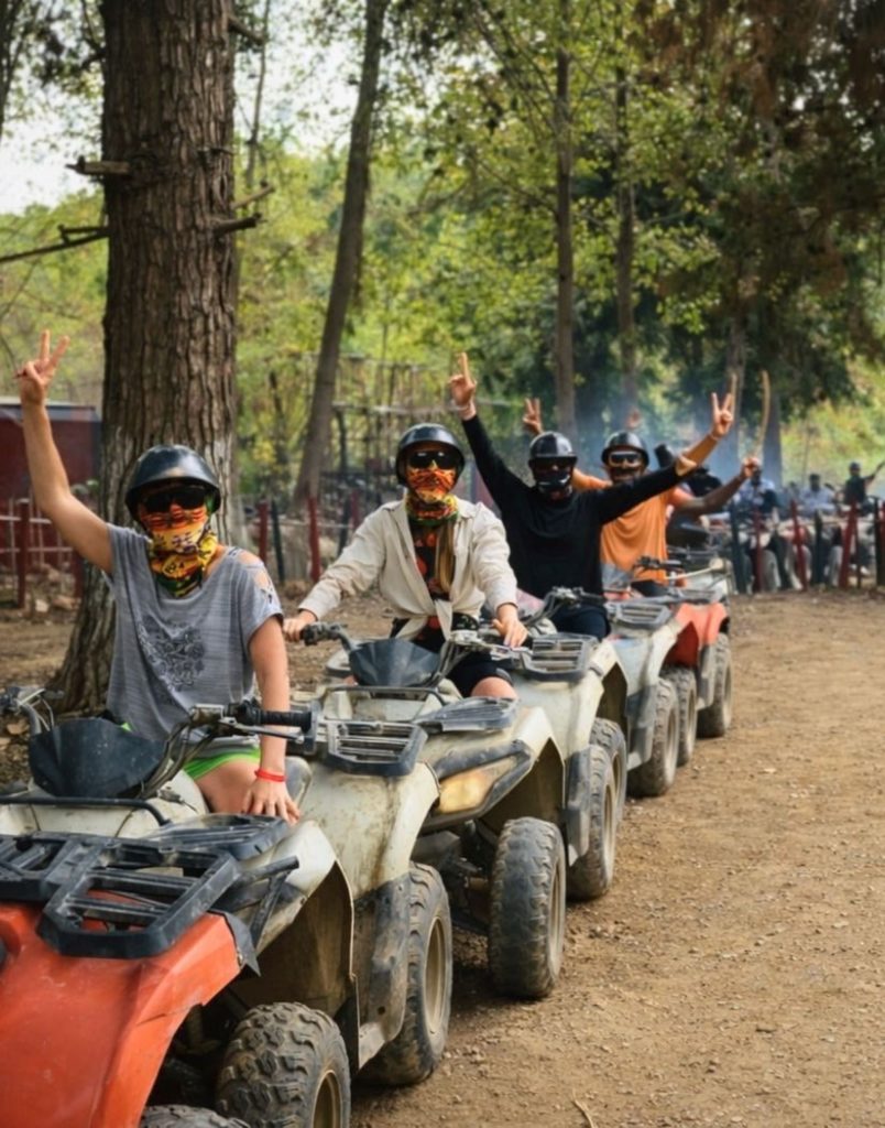 Line of quad riders with colourful bandanas on forest trail in Alanya