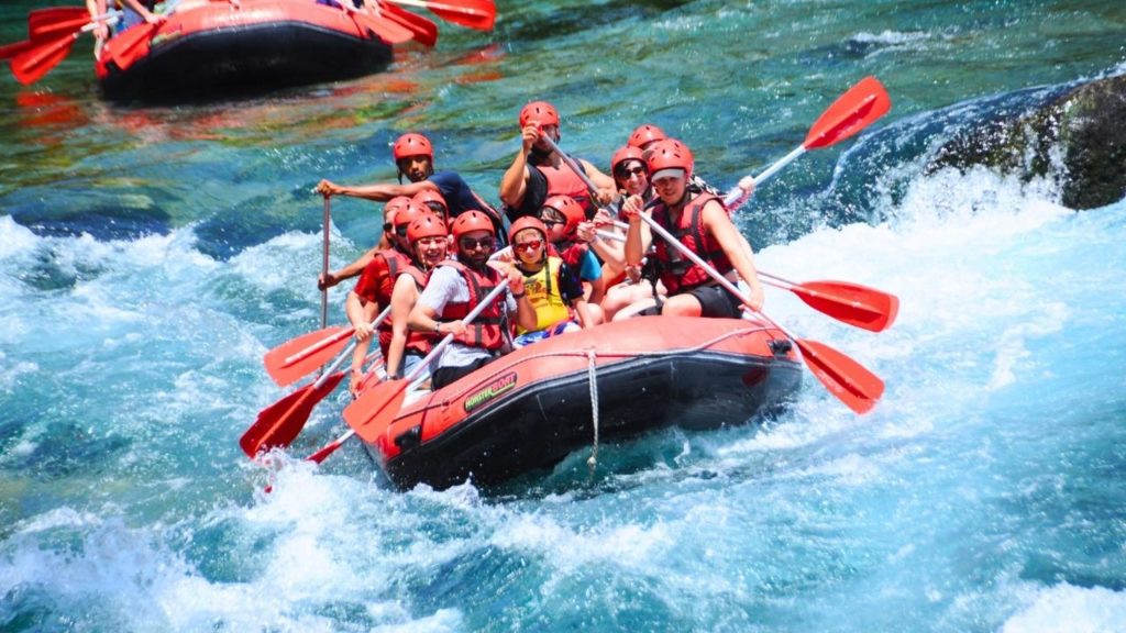 White water rafting on turquoise river with red helmets and paddles near Alanya