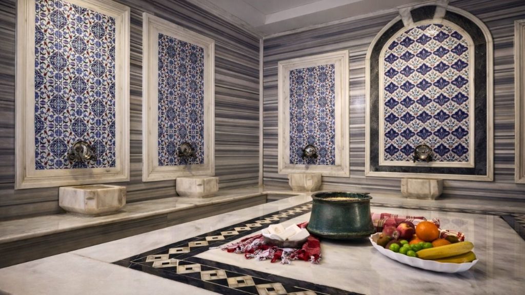 Grand hammam hall with blue Iznik tile panels and heated marble belly stone at Alanya Turkish Bath