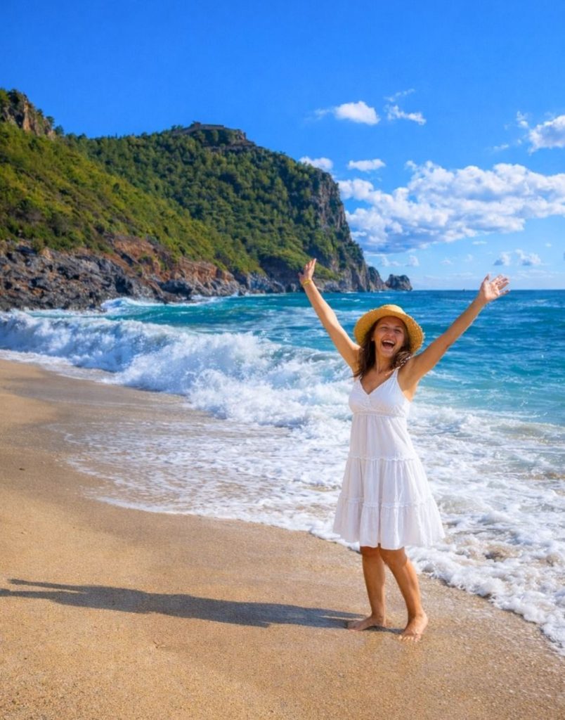 Happy visitor on Cleopatra Beach with castle hill turquoise waves in Alanya