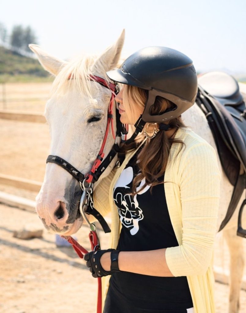 Visitor with helmet meeting white horse at Alanya horse riding ranch