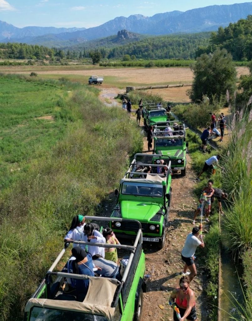 Jeep safari convoy crossing green valley with Taurus Mountain panorama in Antalya