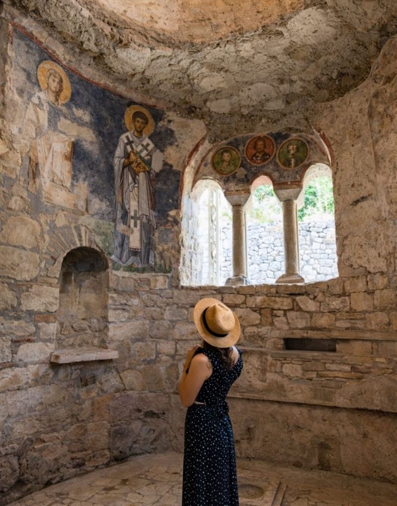 Ancient stone theatre masks at Myra with Lycian rock tombs in background during Demre Myra Kekova Tour