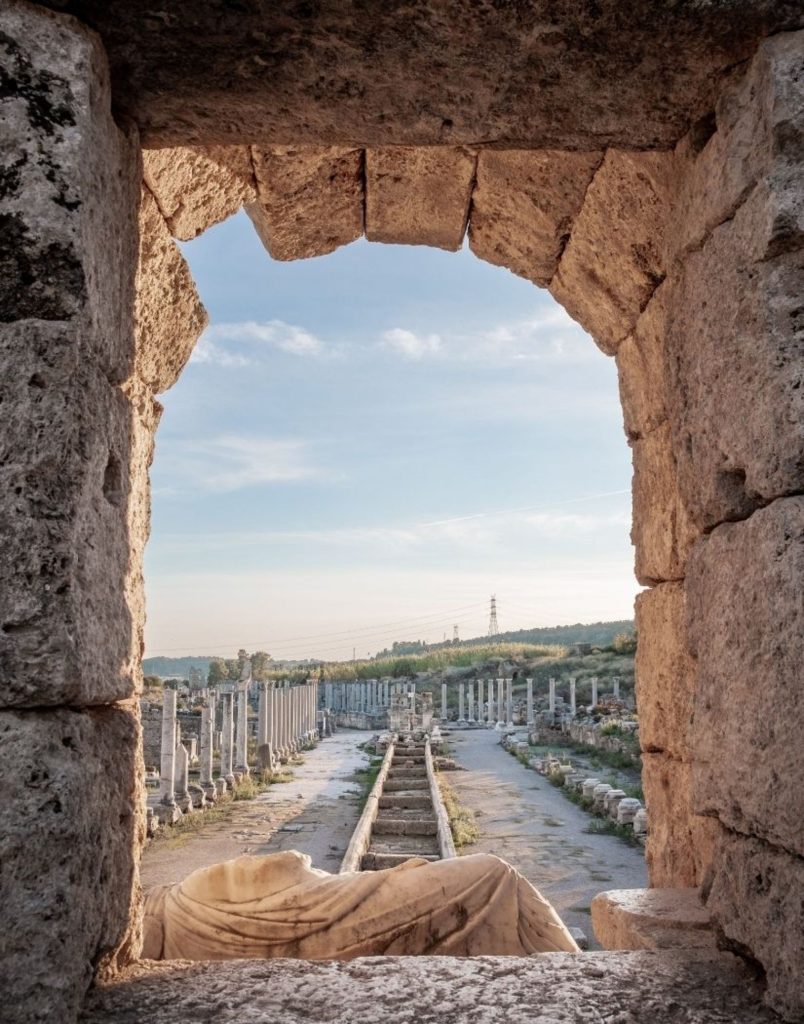 Perge ancient city colonnaded street with Roman columns viewed through a stone arch