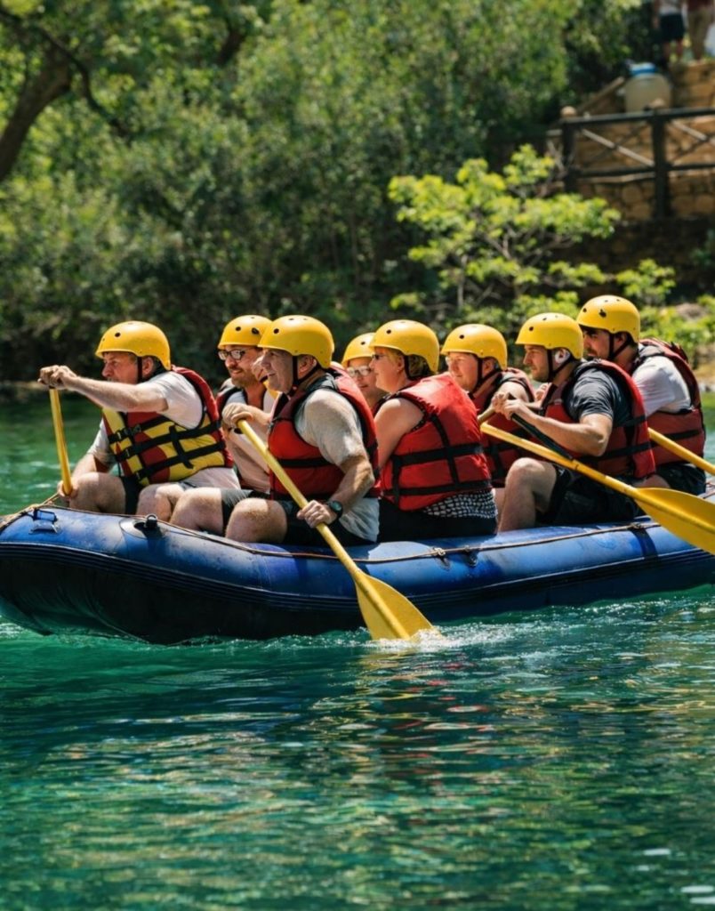 Group rafting through green river waters with helmets and life jackets on Alanya Altinbesik Cave tour