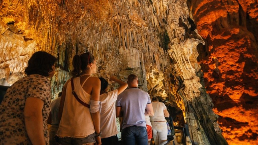 Visitors exploring stalactites inside illuminated Altinbesik Cave on guided tour from Alanya