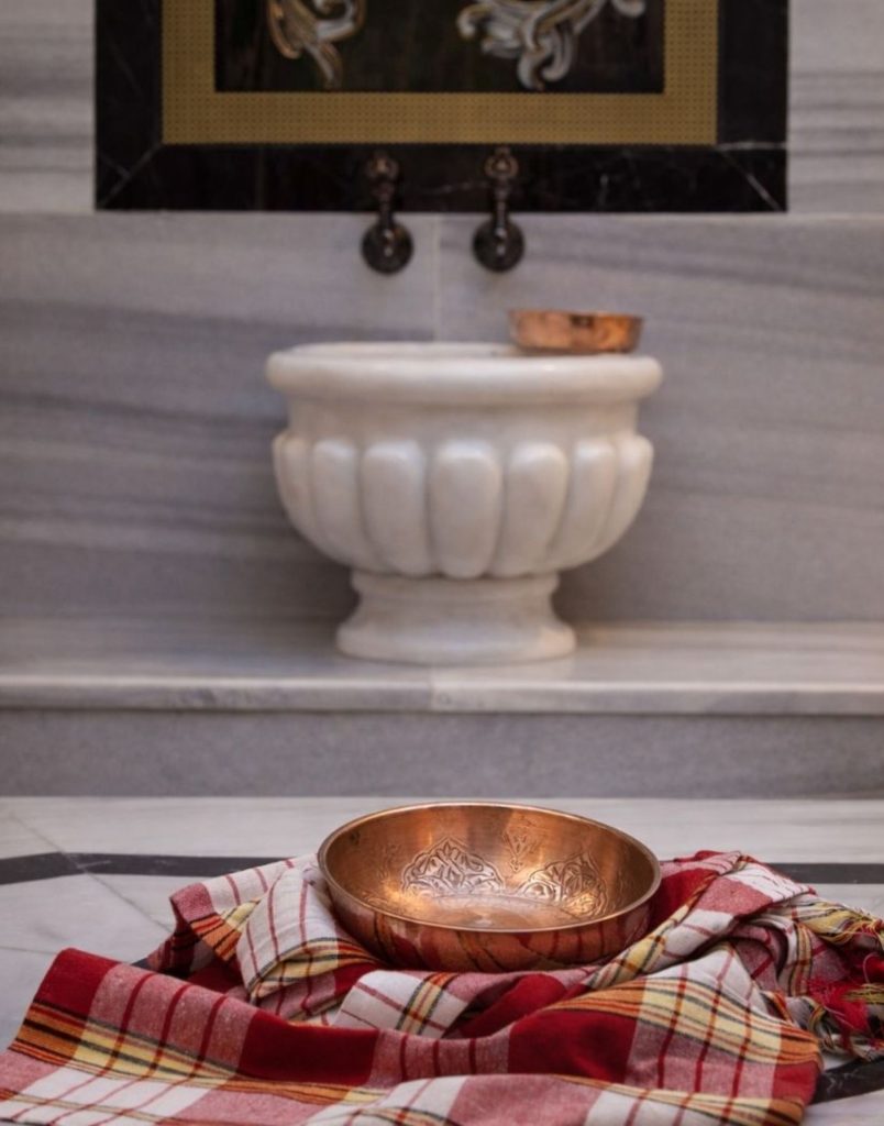 Marble basin with copper bowl and traditional pestemal towel at Belek hammam