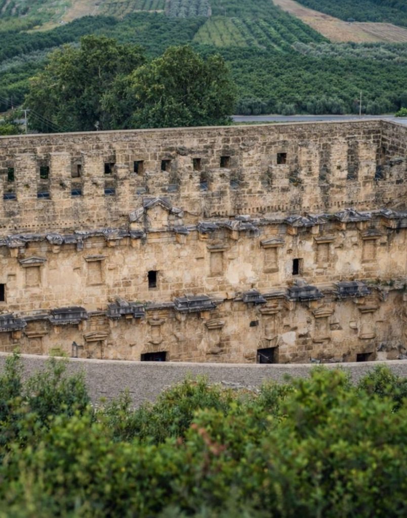 Aspendos Ancient Theatre exterior wall with green orchards and hills behind