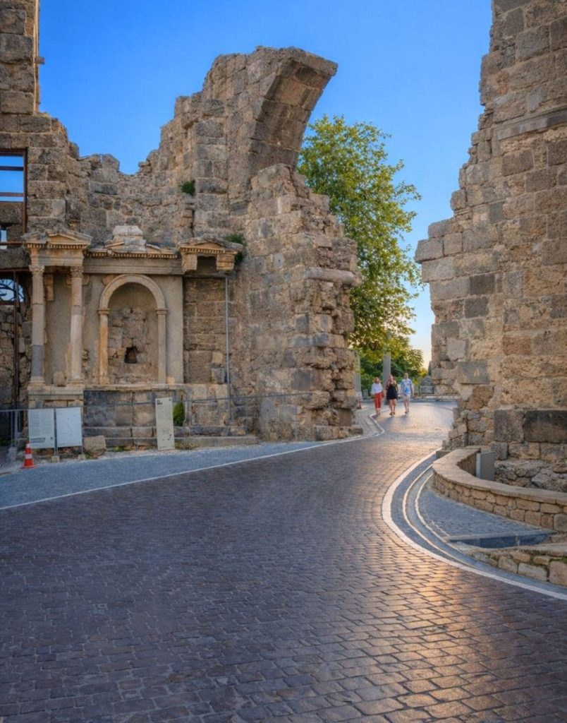 Ancient Side city gate entrance with cobblestone road at golden hour