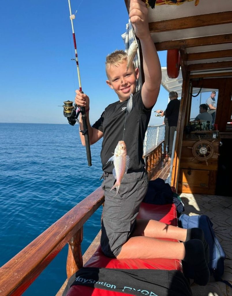 fresh caught fish with fishing rod on wooden boat during sea fishing in side