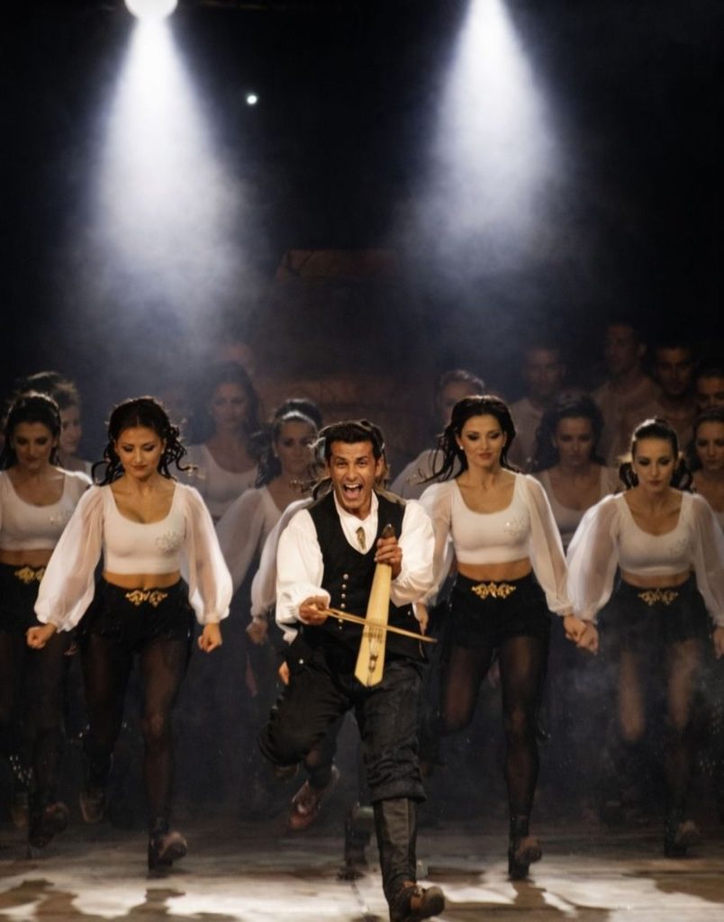 Male dancer with traditional instrument leading folk dance at Fire of Anatolia show