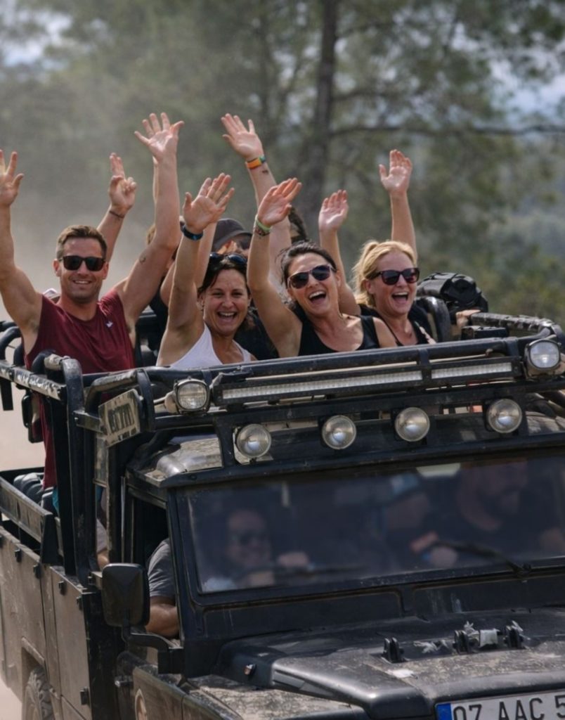 Antalya jeep safari group with hands up on dusty mountain road through Taurus Mountains