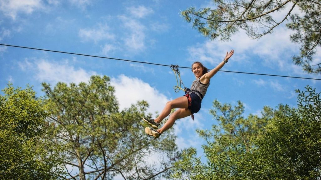Antalya zipline rider flying above pine forest treetops against blue sky on adventure tour