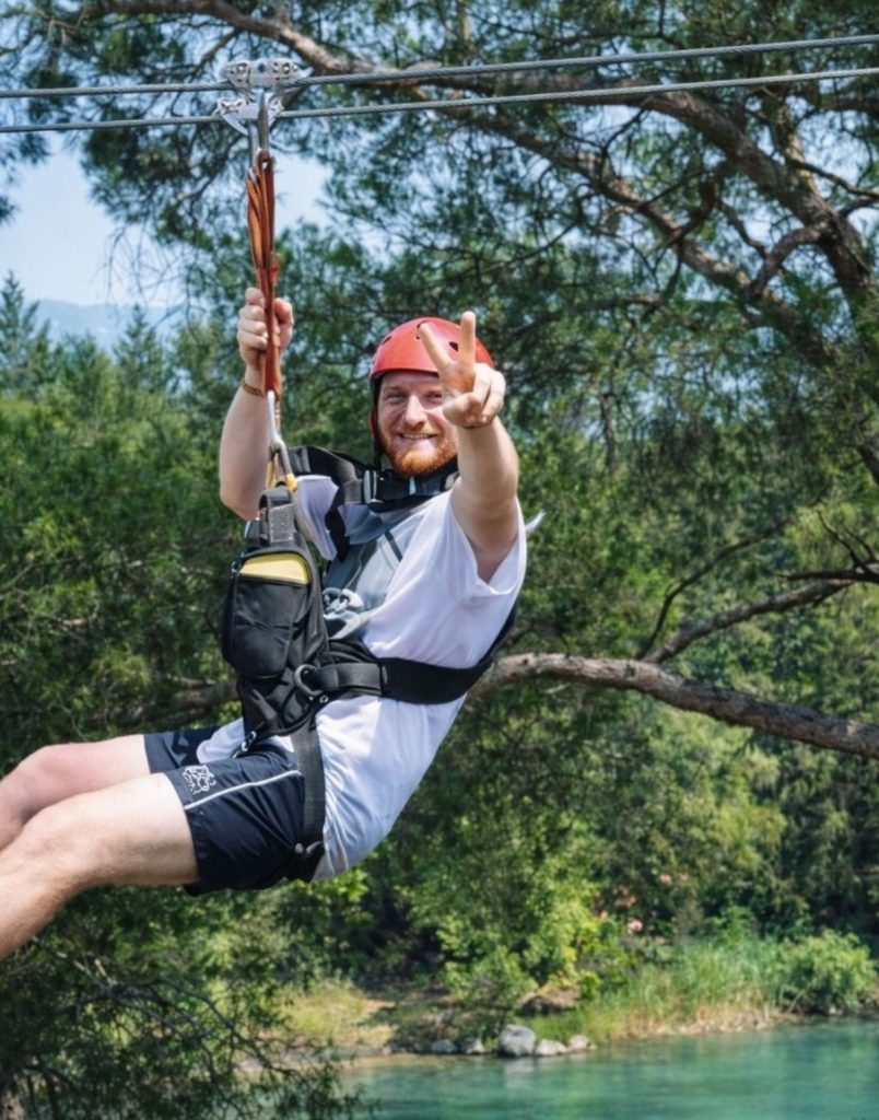 Antalya zipline rider posing over turquoise Koprulu Canyon river with safety harness and helmet