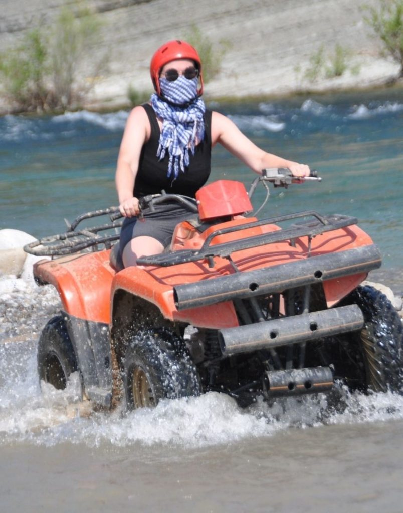 Antalya quad safari rider powering through river crossing with water splash on adventure tour