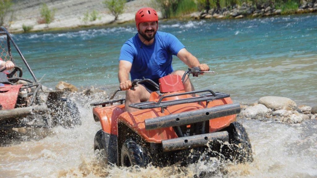 Antalya quad safari rider crossing turquoise river with water splash on adventure tour
