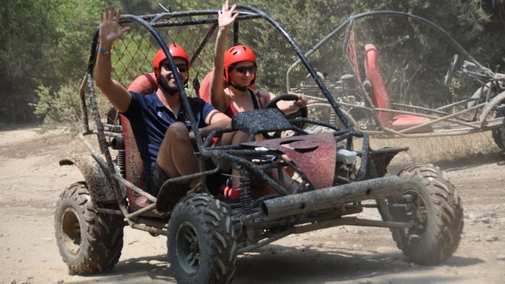 Couple riding a mud-covered buggy on a dirt trail during Antalya buggy safari tour